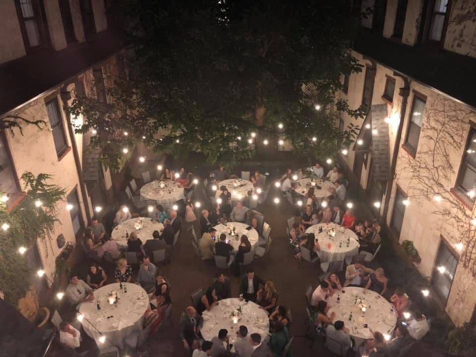 Round tables under string lights for an evening event in the courtyard