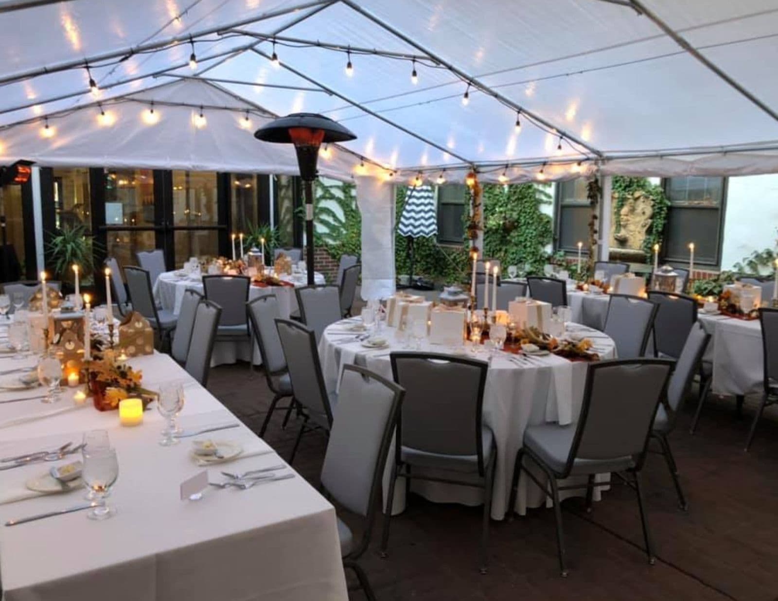 A tented reception in the courtyard, set with round tables and candles